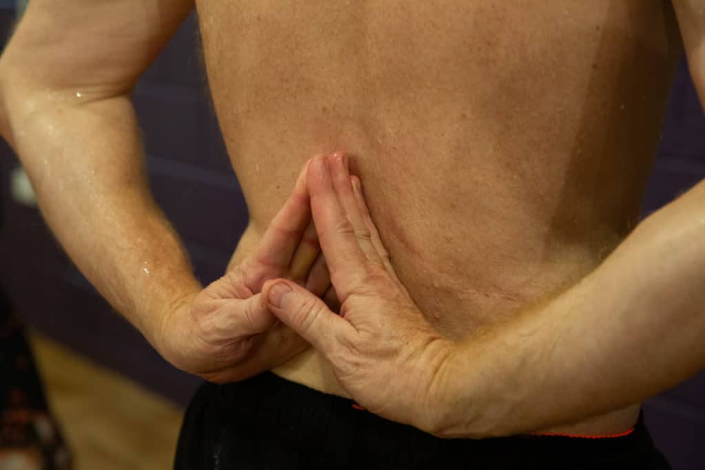 The back of a man practicing a yoga bind in a yoga class in bristol