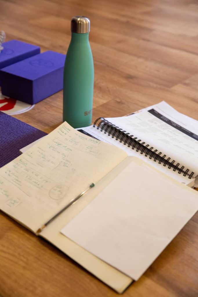 A picture of a notebook, pen and a water bottle from a yoga teacher training course in bristol