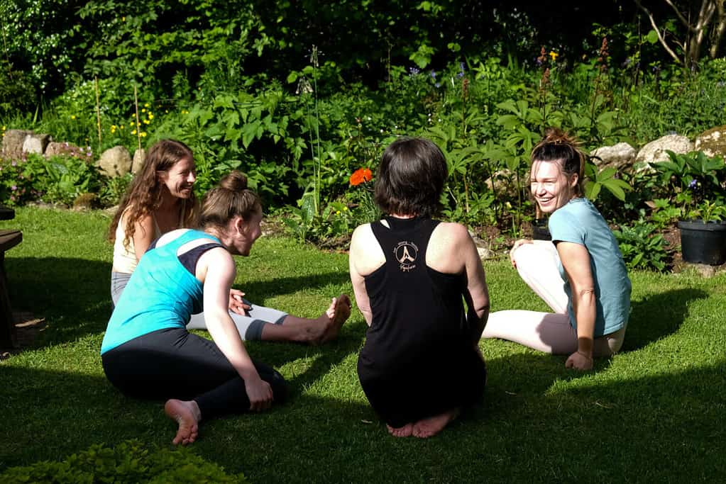 Women sitting in the sunshine in British countryside, laughing and making friends with each other.